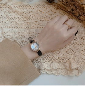 Elegant women's watch featuring a small gold diamond-set case and black slim leather strap