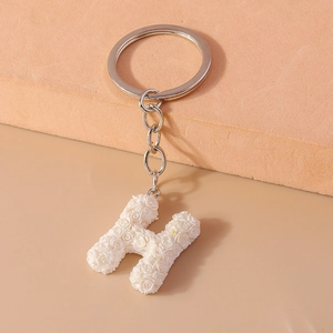 Macro view of alphabet H keychain charm featuring white rose floral relief patterns