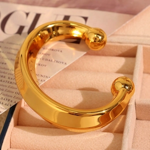 Polished gold thick C-shaped open cuff bracelet presented in a luxury velvet jewelry box