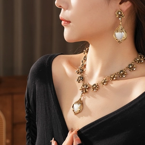 Détail du collier à fleurs vintage en bronze et boucles d'oreilles en perles avec strass brillants