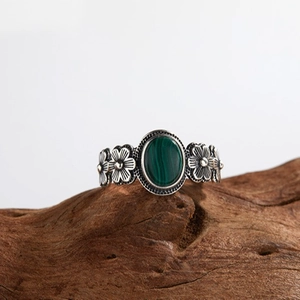 Vintage silver flower ring with oval green malachite stone on natural wood base