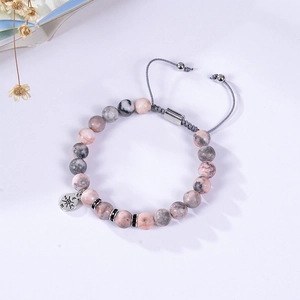 Detailed macro view of pink zebra stone beads and silver compass charm on adjustable bracelet