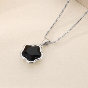Macro shot of silver snake chain featuring a chic black five-petal flower pendant