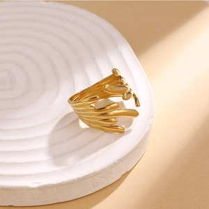 Macro view of a 18K gold-plated irregular fluid ring on a white textured stone tray