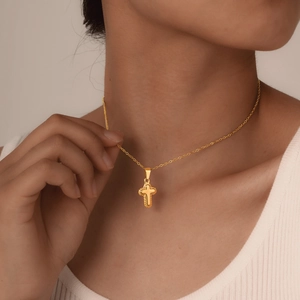 Detail of vintage golden cross pendant with twisted rope texture on a delicate chain