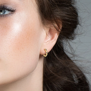 Close-up of gold s925 huggie earrings with blue and white inlaid cubic zirconia