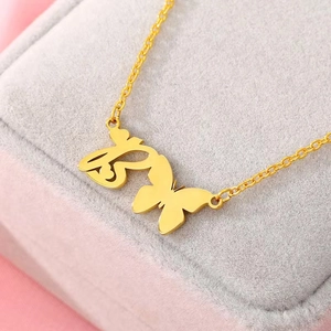 Minimalist gold butterfly necklace with Arabic calligraphy pendant on a velvet box
