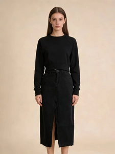 Detail of a high-waisted black denim midi skirt with a stylish front slit and raw hemline