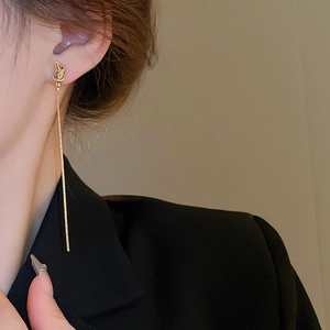 Gros plan de boucles d'oreilles nœud doré avec de longs glands sur un modèle