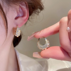 Gold-plated handbag style huggie earrings with cubic zirconia stones on model