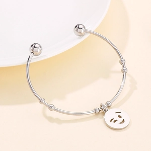 Detailed view of silver titanium steel open bangle with a playful winking smiley face charm