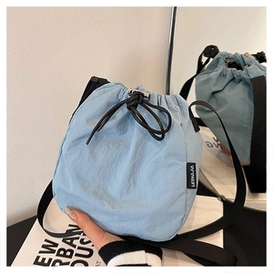 Detail of light blue nylon drawstring bucket bag with black strap and brand tag