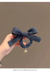 Détail d'un chouchou en jean avec un pendentif cloche dorée et texture en tissu bleu