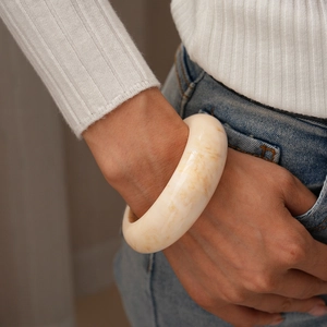Détail du bracelet épais en résine crème avec texture ambre porté par un mannequin