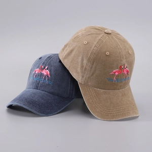 Detail of embroidered flamingo pattern on washed cotton baseball caps in navy and khaki