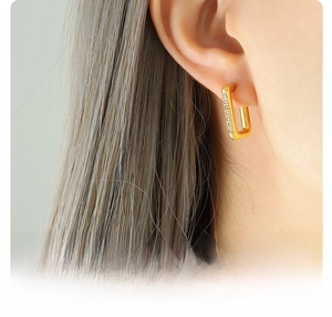 Détail de créoles en acier titane plaqué or 18 carats avec zircon incrusté sur l'oreille