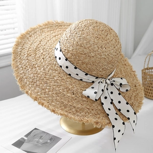 Chic raffia sun hat with a polka dot ribbon and wide brim for summer travel