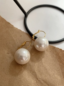 Close-up of 14K gold plated pearl earrings on vintage paper with natural lighting