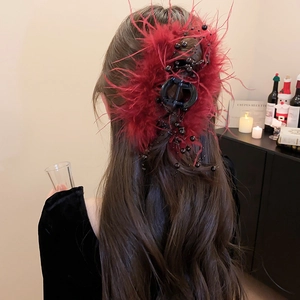 Close-up of red feather hair claw clip with black beads on long wavy hair back view