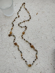 Detail of multi-bead long necklace with natural marble stones and brown jasper accents