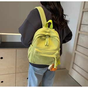 Detail of yellow corduroy backpack featuring weave zipper pulls and knit carrot charms
