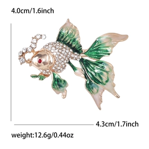 Broche poisson rouge dorée avec émail vert, strass et yeux en gemmes rouges sur blanc