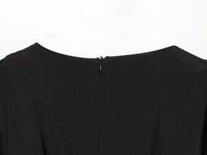 Détail de la fermeture éclair invisible et du tissu tissé sur cette robe plissée noire