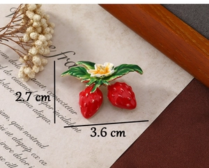 Detail showing red strawberry brooch size 2.7x3.6 cm on a rustic vintage background