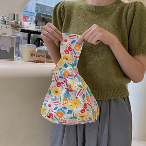 Close-up of a floral canvas wristlet bag with a unique knotted handle in a cafe setting