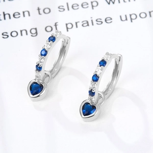 Macro shot of silver heart hoop earrings with blue gemstones and clear zircon stones
