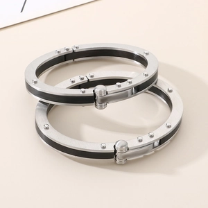 Detail showing industrial brushed steel bangle with black accents and rivet decoration