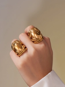 Detailed macro view of two chunky 18k gold plated stainless steel rings with vintage carvings