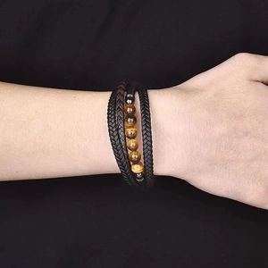 Détail d'un bracelet multi-rangs en cuir noir avec perles en œil de tigre marron
