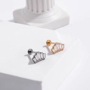 Macro detail of Fan-shaped G23 titanium labret studs with zircon gems on white pedestal