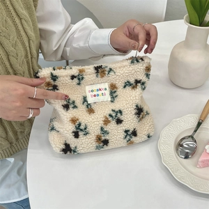 Detail of plush floral cosmetic bag showing soft lambskin texture and logo label