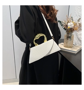 Detail of white crocodile pattern bag with gold metal handle and shoulder strap