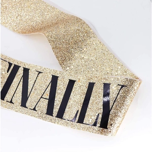 Macro view of gold glitter birthday sash texture with bold black INALLY lettering print
