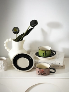 Artistic detail of vintage hand-painted floral ceramic coffee cups and saucer set on display