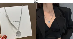 Detail view of silver hip-hop necklace with asymmetric chain and vintage round tag