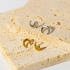Close-up of geometric curved moon stud earrings in gold and silver on a stone display
