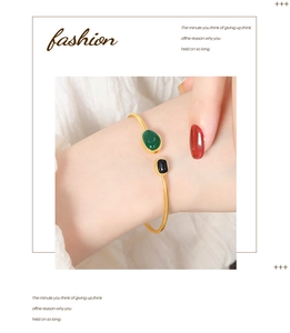 Detail view of a vintage gold bangle with green teardrop and black onyx-style stones