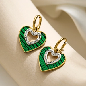 Elegant gold hoop earrings with green heart pendant and shell inlay on a jewelry stand