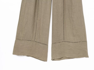 Dettaglio dei pantaloni in lino kaki a gamba larga con ricamo traforato sull'orlo inferiore