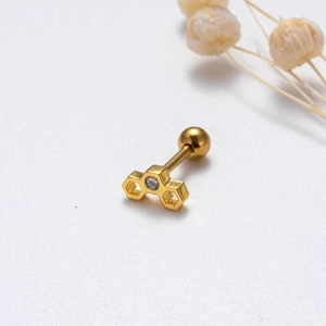 Detailed view of golden honeycomb stud earring with a clear gemstone on white background