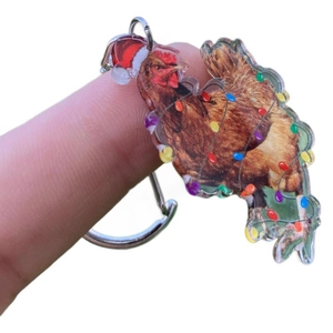 Acrylic Christmas chicken keychain with Santa hat and lights held against white background