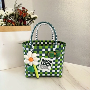 Green and white plaid woven picnic basket with daisy decor on marble surface
