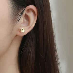 Macro shot of gold-plated screw-shaped stud earring worn on earlobe for detail