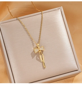 Gros plan du collier pendentif nœud doré avec zircons sur fond de soie