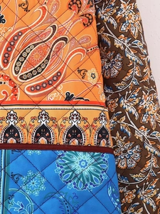 Detail of quilted fabric featuring paisley and floral patchwork with diamond stitching