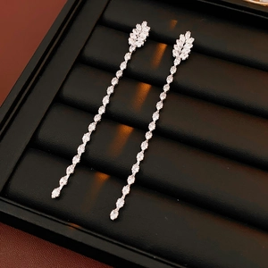 Macro shot of silver zircon chain tassel earrings with leaf design on black display